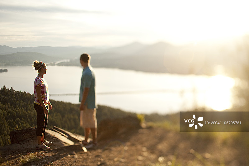 在悬崖边欣赏湖景的两名年轻人图片素材
