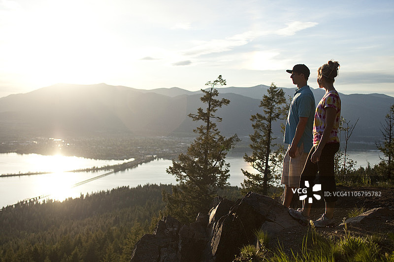 在悬崖边欣赏湖景的两名年轻人图片素材