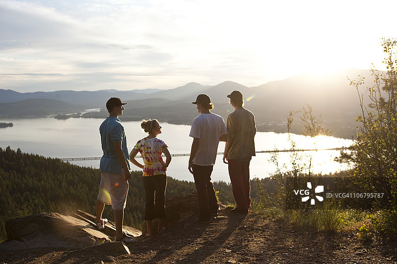 四个年轻朋友在日落后徒步旅行，欣赏风景图片素材