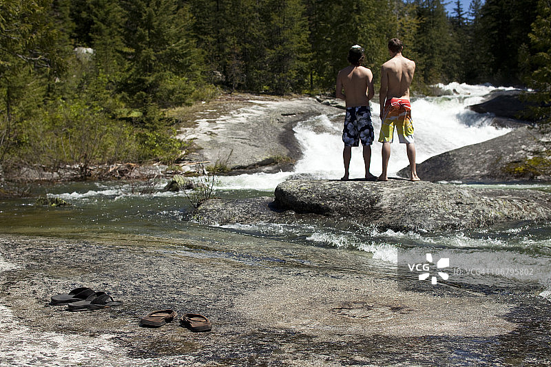 两名年轻男子站在小岛上讨论跳入冰冷的河中图片素材