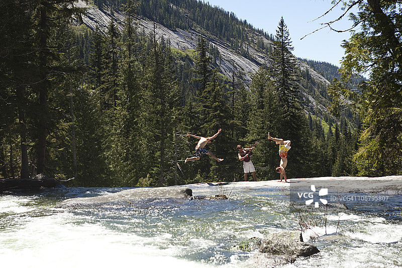 三个年轻男人在爱达荷州一条河边跳舞和听吉他图片素材