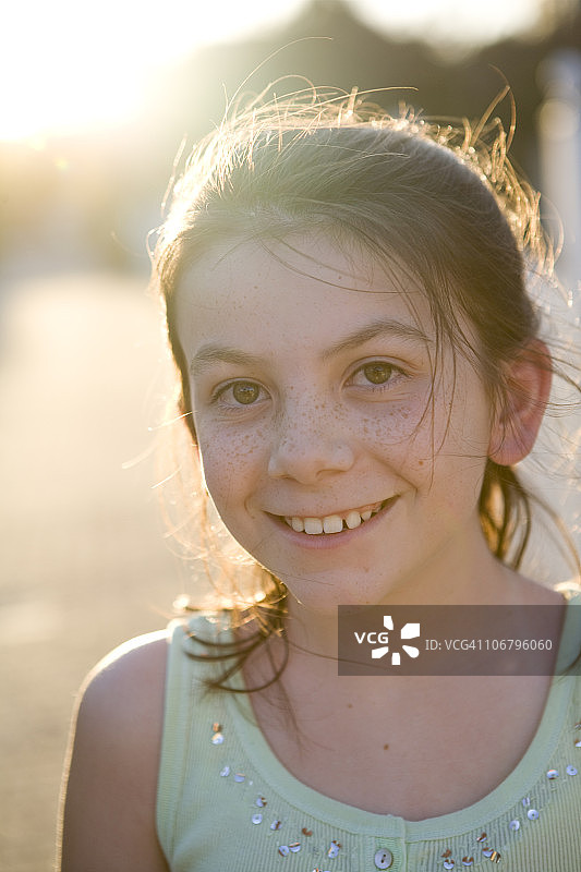 阳光下，带着雀斑的小女孩对着镜头微笑图片素材