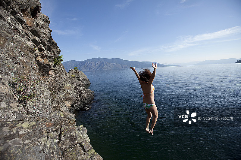 女人从爱达荷州的一个小悬崖跳入湖中图片素材