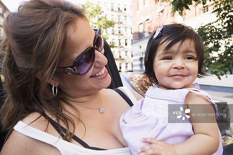 城市街道上微笑的西班牙裔母女图片素材