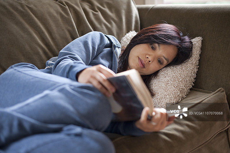 女人在沙发上放松看书图片素材