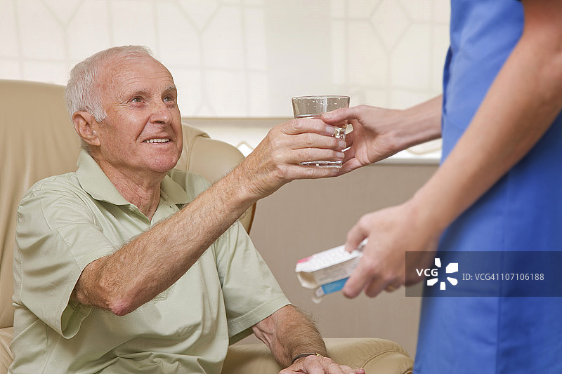 护理人员给年长男人水和药片图片素材