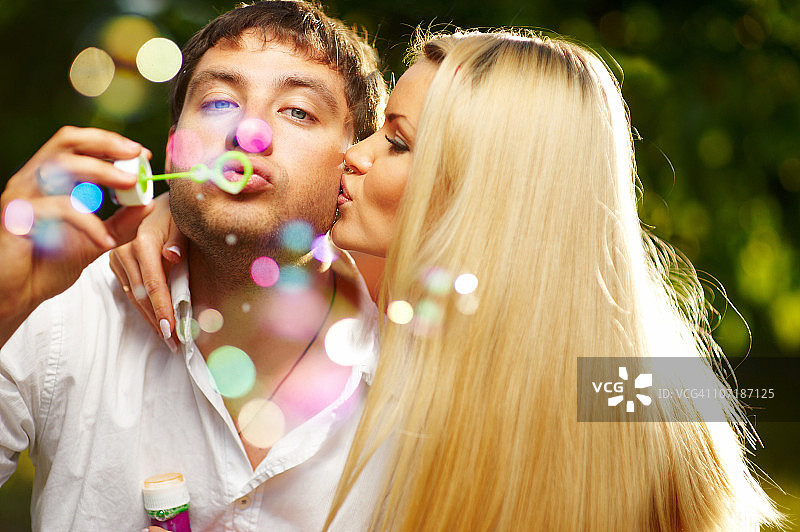 女人亲吻正在吹泡泡的男人图片素材
