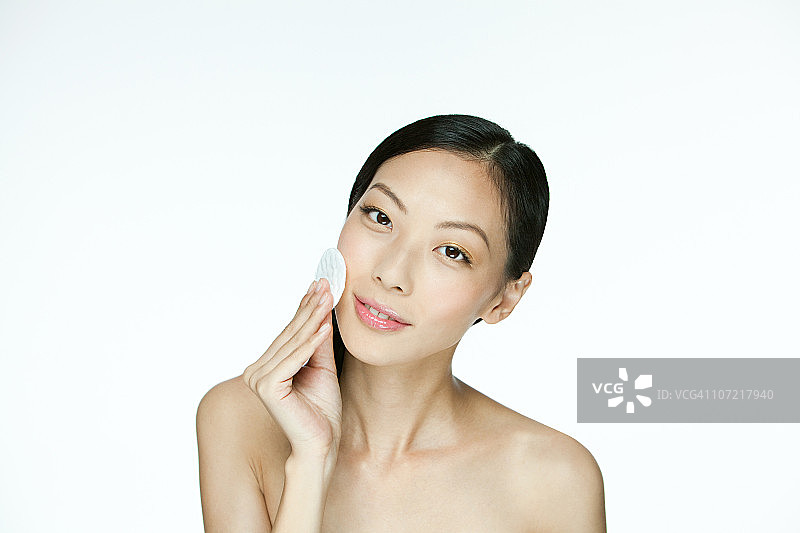 年轻女子在脸上使用化妆棉图片素材