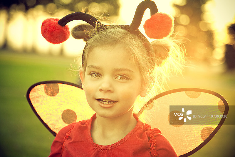 日落时身穿瓢虫服装的学龄前女孩图片素材