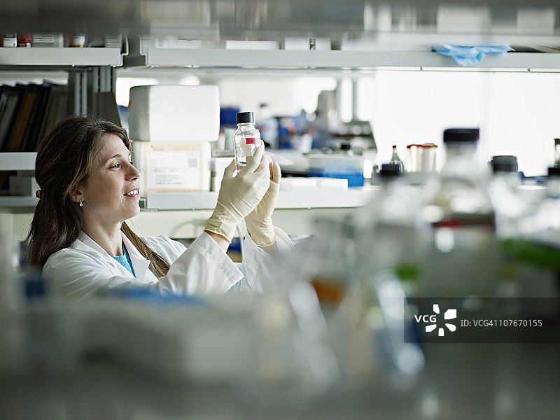 女科学家在研究实验室检查试剂瓶图片素材