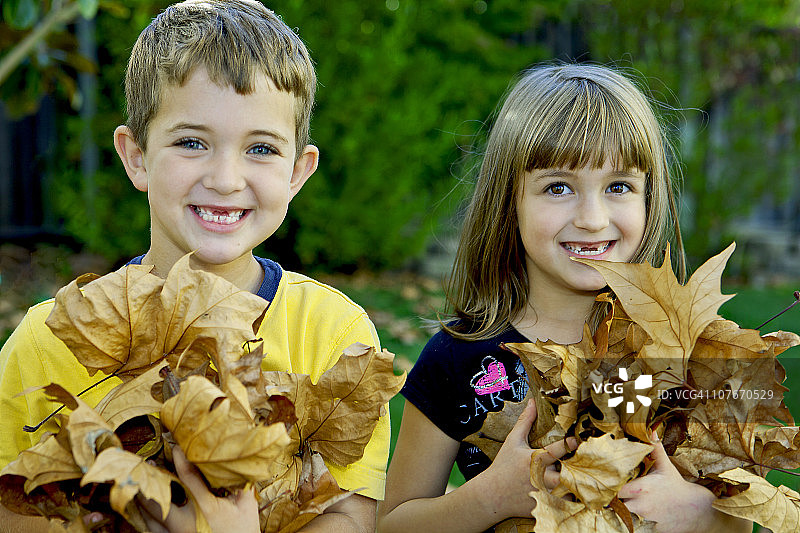 拿着树叶的男孩和女孩图片素材