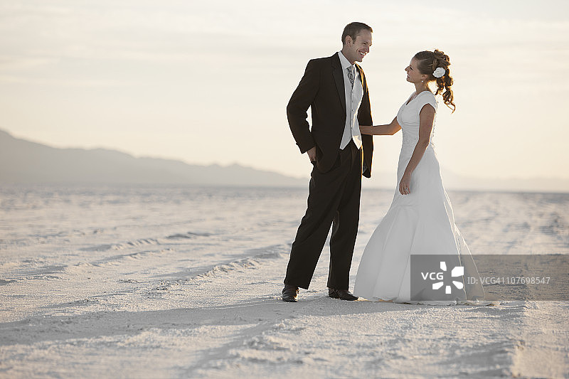 美国犹他州博纳维尔盐滩，新娘和新郎站在沙漠中图片素材