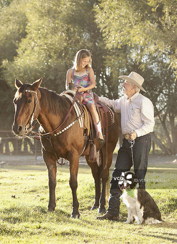 美国犹他州利海，老人带狗帮助孙女（8-9岁）在牧场骑马图片素材