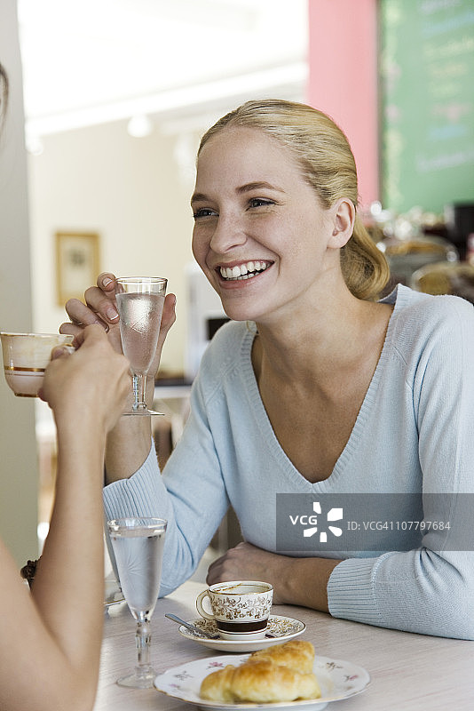 年轻女子和朋友在咖啡馆里坐着图片素材