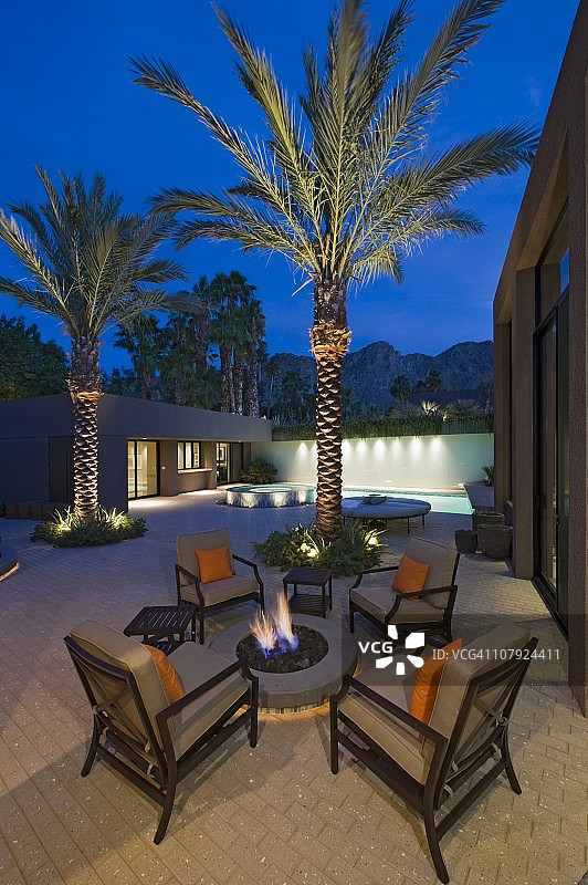 加州住宅露台上，棕榈树在火坑旁点亮，配有椅子图片素材