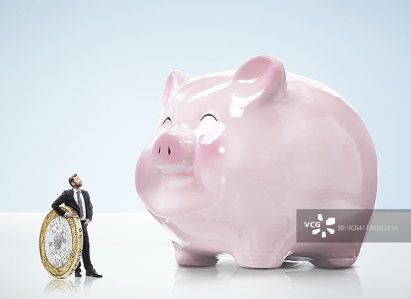 手持硬币看储蓄罐的商人图片素材