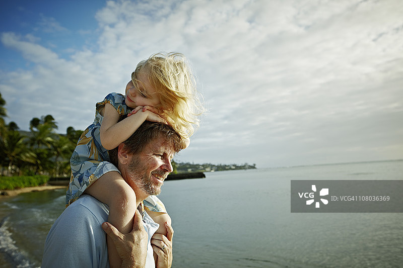 女儿在海滩上骑在父亲的肩膀上图片素材