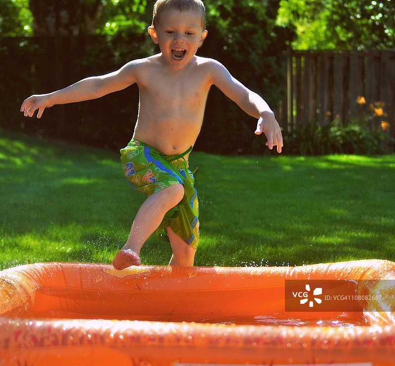 男孩在泳池里跳跃图片素材