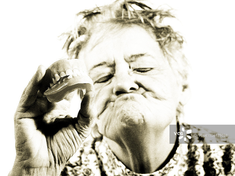年长妇女拿着假牙，棕褐色调图片素材