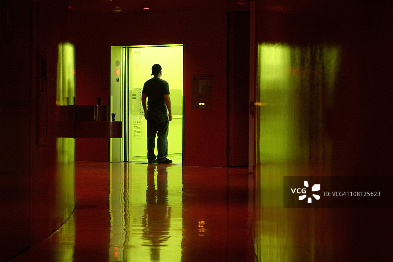 年轻男人从黑暗走廊进入电梯图片素材