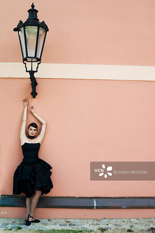 站在壁灯旁的年轻女子图片素材