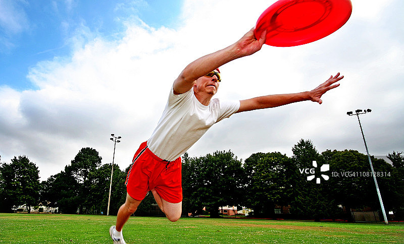 年轻男人在田野里跳跃接飞盘图片素材