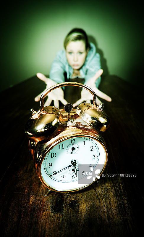 年轻女子伸手去拿时钟图片素材