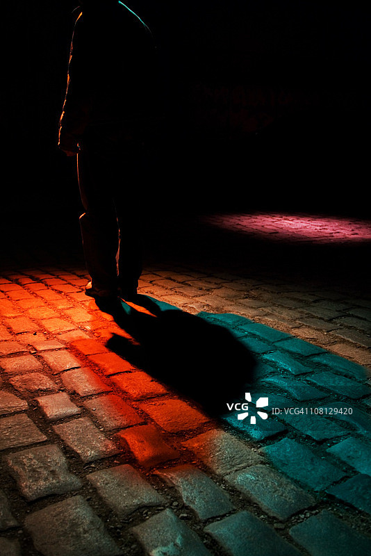 暗调下走在昏暗鹅卵石街道的男人图片素材