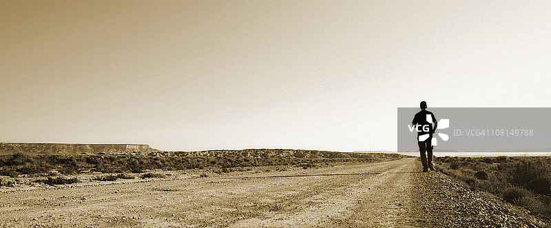 在沙漠中奔跑的年轻男人，棕褐色调图片素材