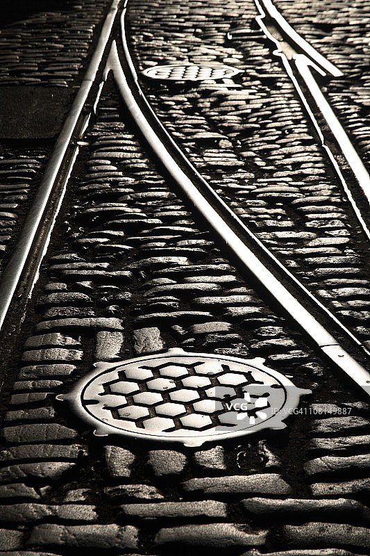 鹅卵石街道上的铁轨和井盖图片素材