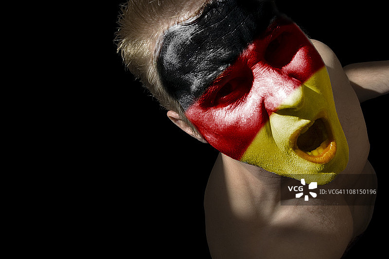 脸上涂有德国国旗颜色的男人，黑色背景图片素材