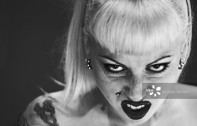 化妆和面部穿孔的女人做鬼脸图片素材
