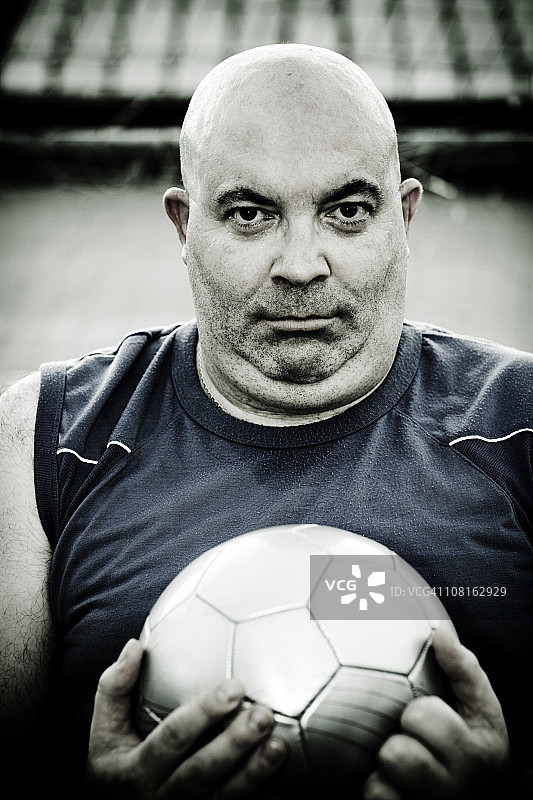 秃顶男子抱着足球图片素材