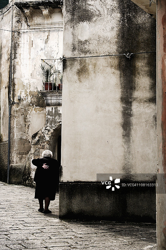 年长的女人在西西里小镇散步图片素材