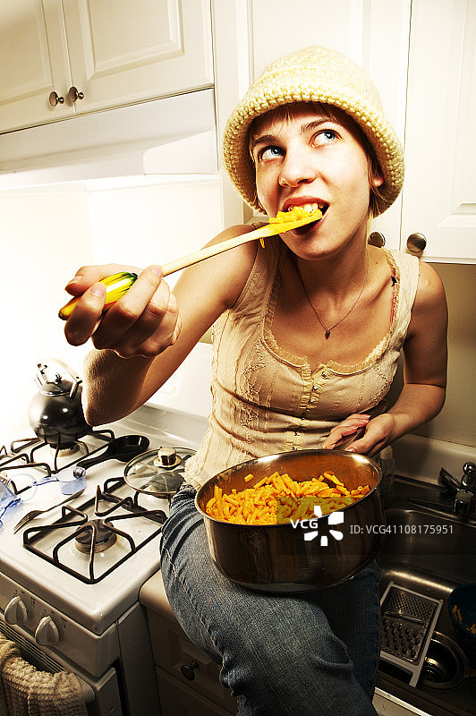 年轻女人在锅里吃通心粉和奶酪图片素材