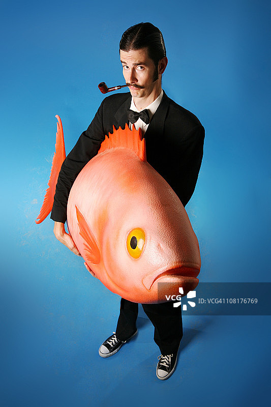 抽烟斗并扛着大鱼的男人图片素材