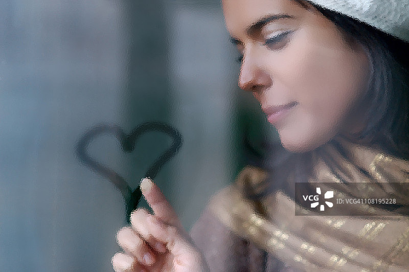 年轻女人在雾窗上画爱心图片素材