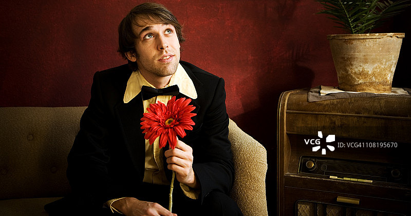 穿着燕尾服并拿着大花的年轻男人图片素材