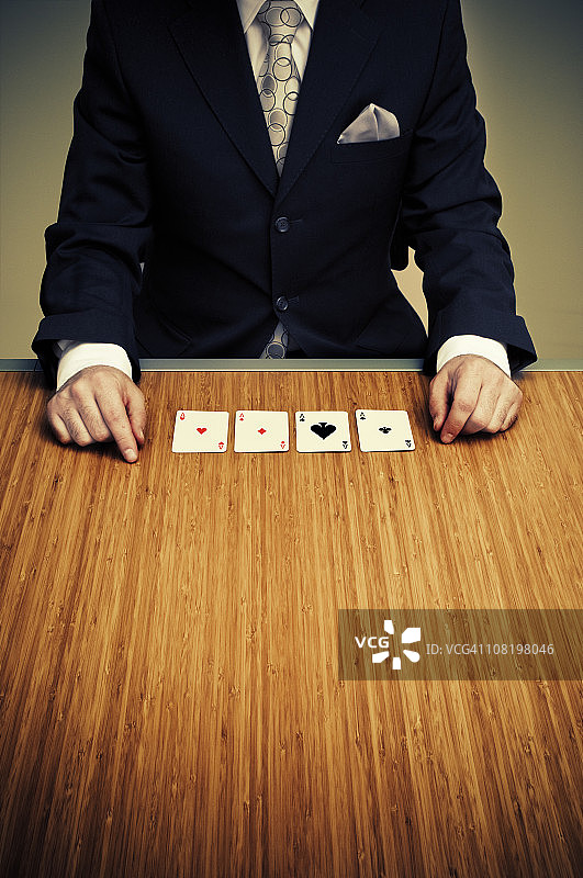 坐在桌旁手持四张Aces的商人图片素材