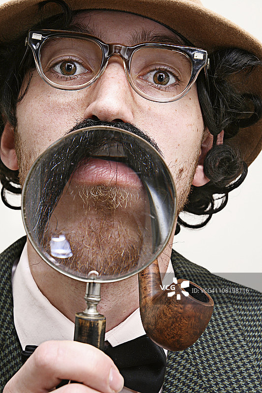 留着胡子、叼着烟斗、拿着放大镜的侦探图片素材