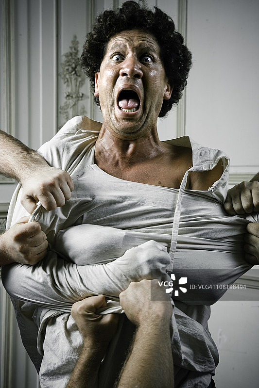 人们抓住穿着束身衣的愤怒的年轻人图片素材