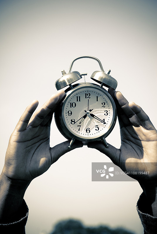 双手拿着闹钟图片素材