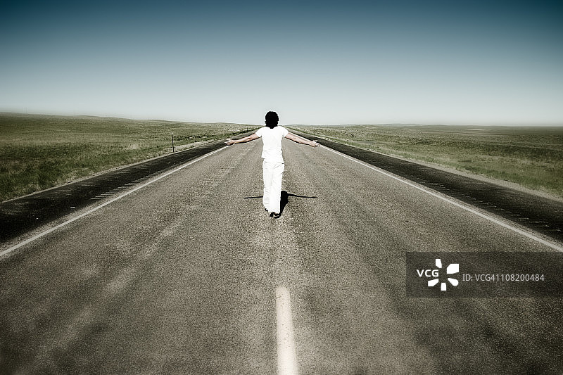 在空旷的道路上伸展双臂行走的人图片素材