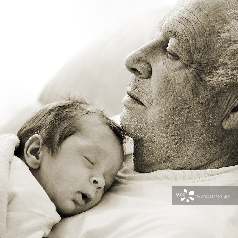 睡着的新生婴儿躺在年长男人胸前图片素材