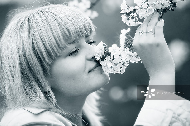 手捧鲜花并嗅闻的年轻女子图片素材
