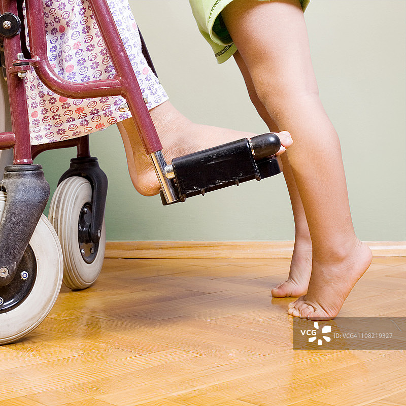 站在轮椅前踮起脚尖的儿童图片素材