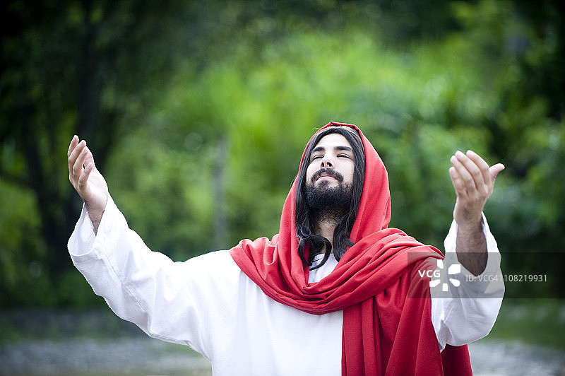 长相酷似耶稣基督的男人在户外祈祷图片素材