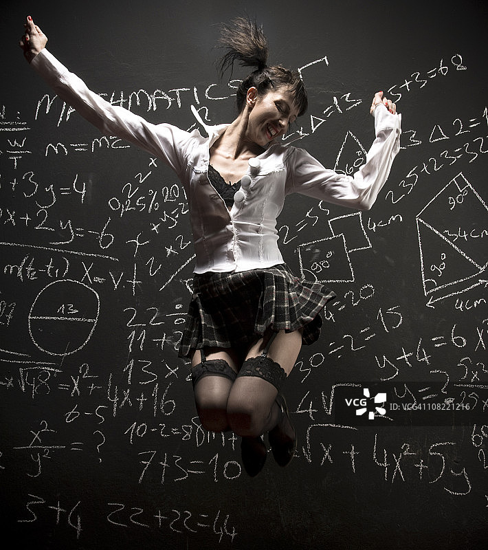 穿着校服在黑板前跳跃的女人图片素材