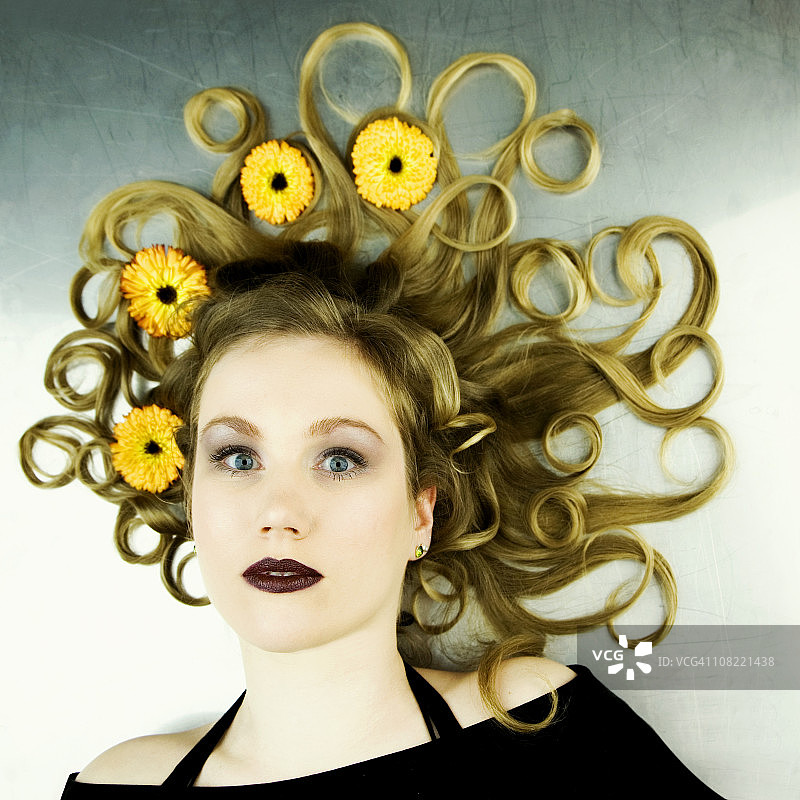 年轻女子躺下，卷发中戴着鲜花图片素材