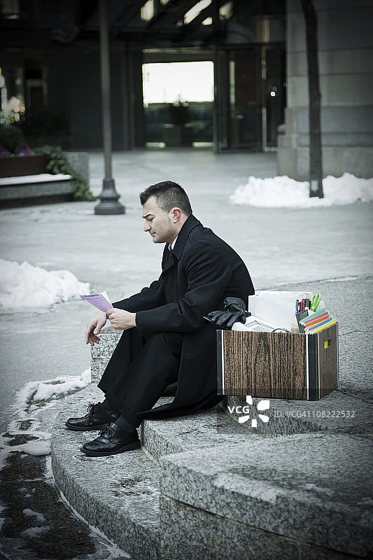 坐在户外楼梯上的沮丧商人与包装盒图片素材